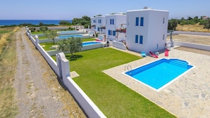 A coastal hotel with multiple white buildings, a central swimming pool, and a clear view of the sea. - White House Villas (Rhodes)