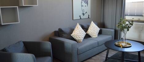 A modern living room with a grey sofa, two matching armchairs, and a coffee table with a tray.