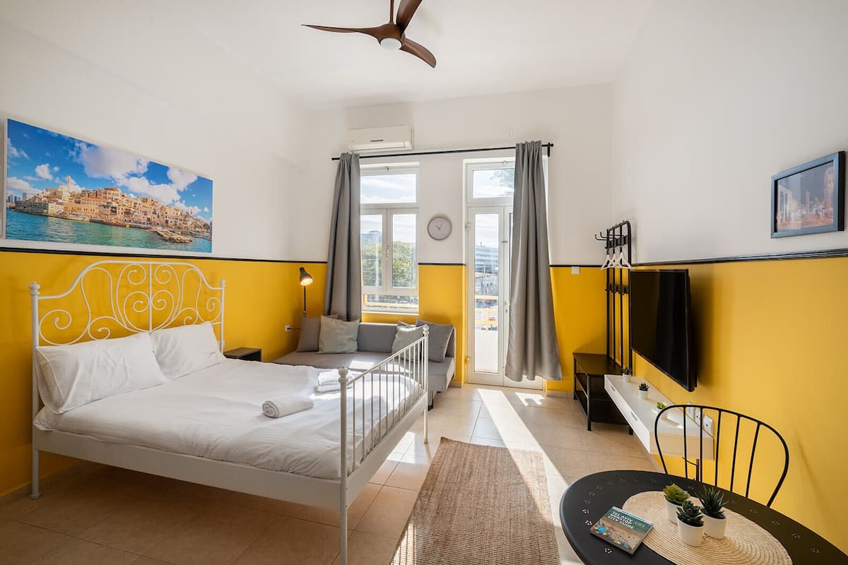 A hotel room with a bed, a desk, a chair, a TV, and a window with curtains.