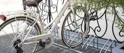 Ein weißes Fahrrad mit Korb und Sattel, an einem Metallzaun geparkt.