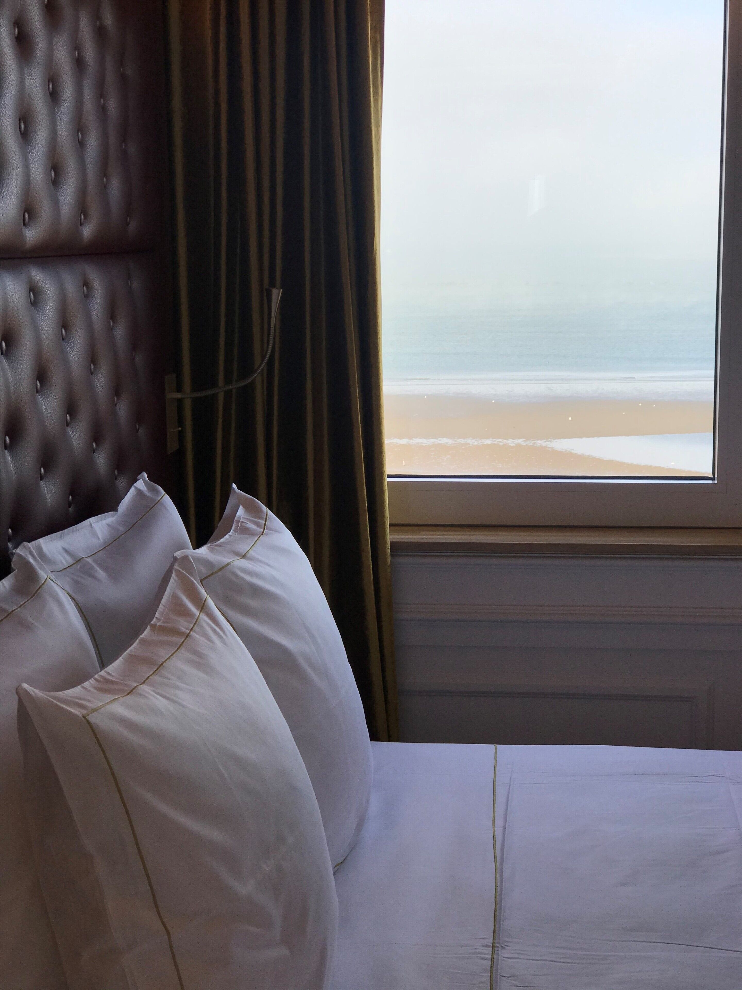 Una habitación de hotel con cama, cabecera y vista a la playa.