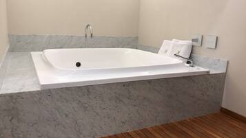 Une salle de bain moderne avec une baignoire rectangulaire, des plans de travail en marbre et un plancher en bois.
