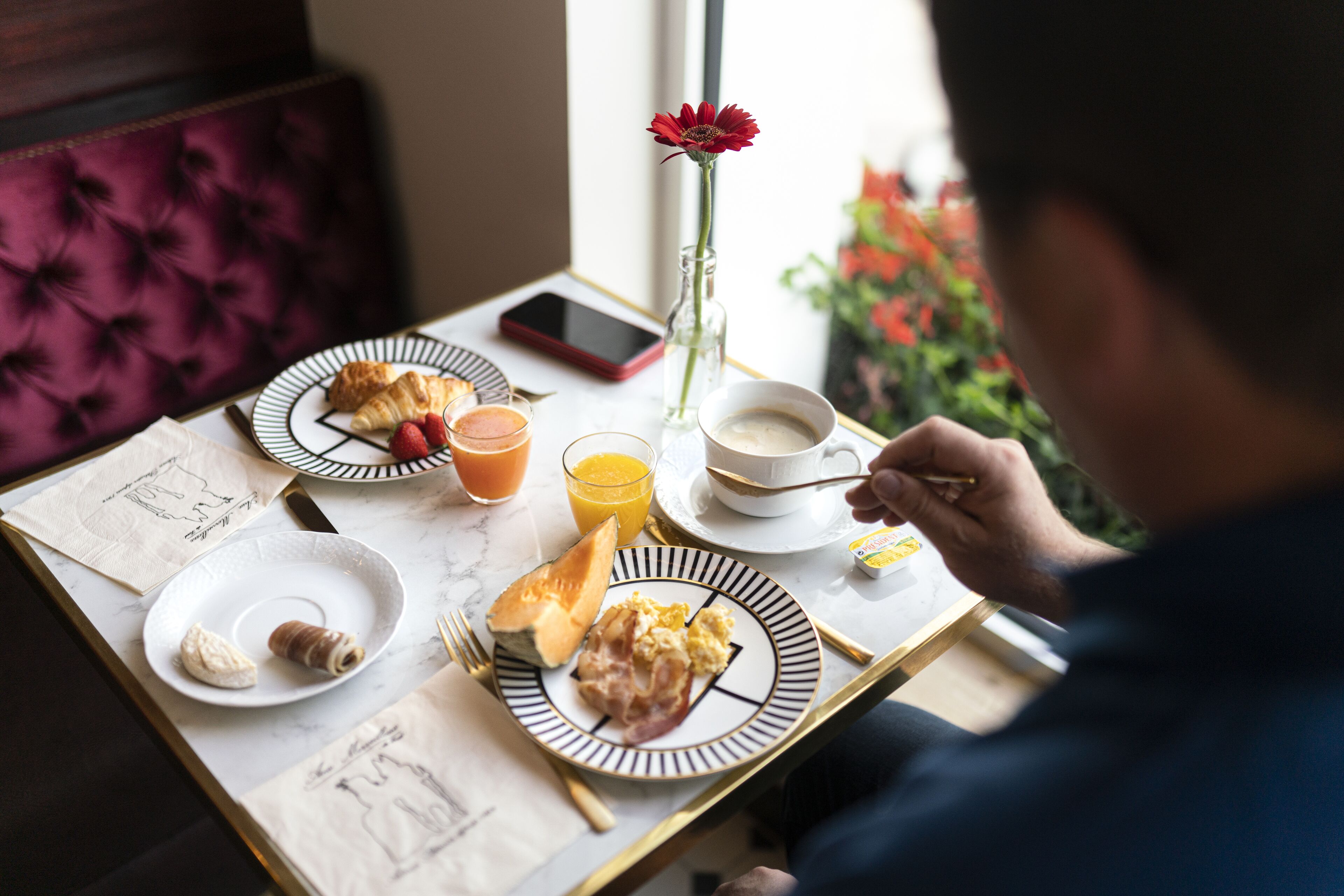Une table de petit-déjeuner avec des croissants, des fraises, du jus d’orange et du café.
