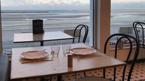 A table set with chopsticks, a plate, and glasses, overlooking a beach with a clear sky. - Hotel Merveilleux Côté Mer (Dunkirk)