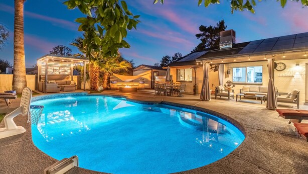 Une piscine dotée d’un espace salon aménagé en contrebas, de mobilier d’extérieur et d’un patio couvert.