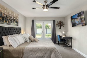 A bedroom with a bed, a desk, a chair, a ceiling fan, and a view through the door. - "Kings" Modern Retreat | Heated Pool & Fire Pit (Scottsdale)