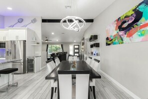 Enjoy meals at the sleek dining table surrounded by stainless steel appliances and a vibrant abstract painting.