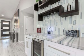 A modern kitchen with a marble countertop, a built-in oven, and a glass display case.