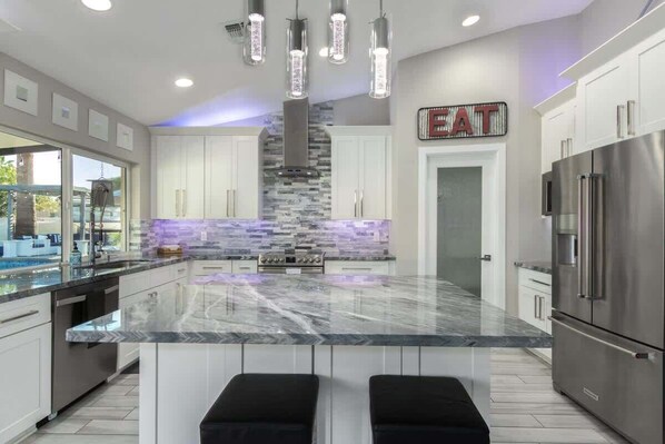 A modern kitchen with a central island, stainless steel appliances, and pendant lighting.