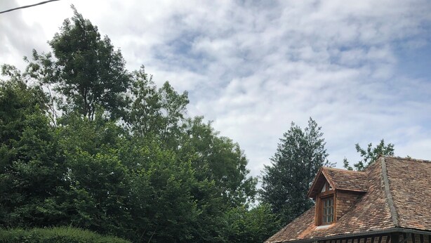 Una casa tradicional con entramado de madera, un camino de grava, un pequeño jardín y un césped.