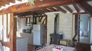 Una cocina rústica con techo de madera, un refrigerador, una estufa y una mesa de comedor con mantel a cuadros.
