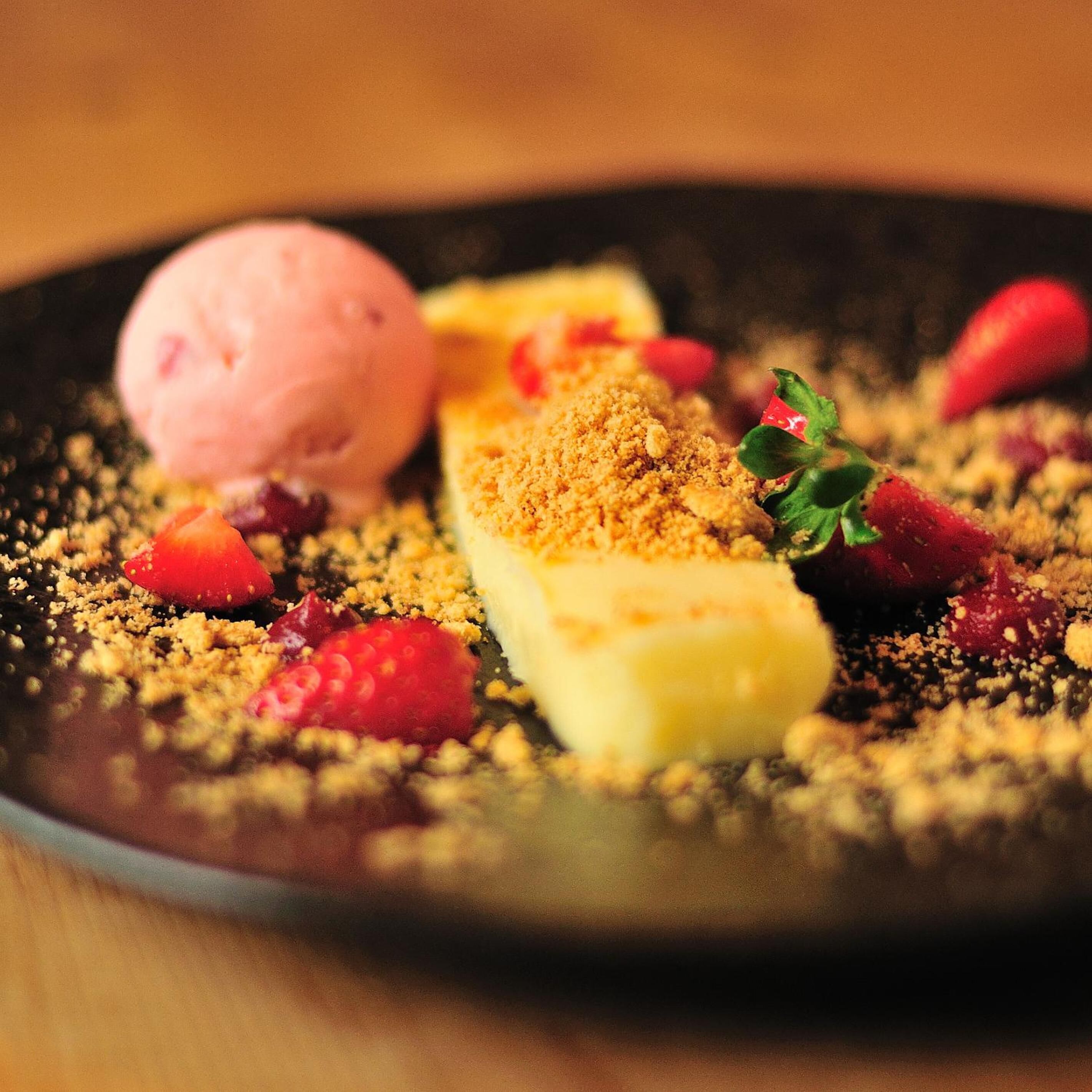 Ein Dessertteller mit einer Kugel Eis, ein Stück Kuchen und Erdbeeren.
