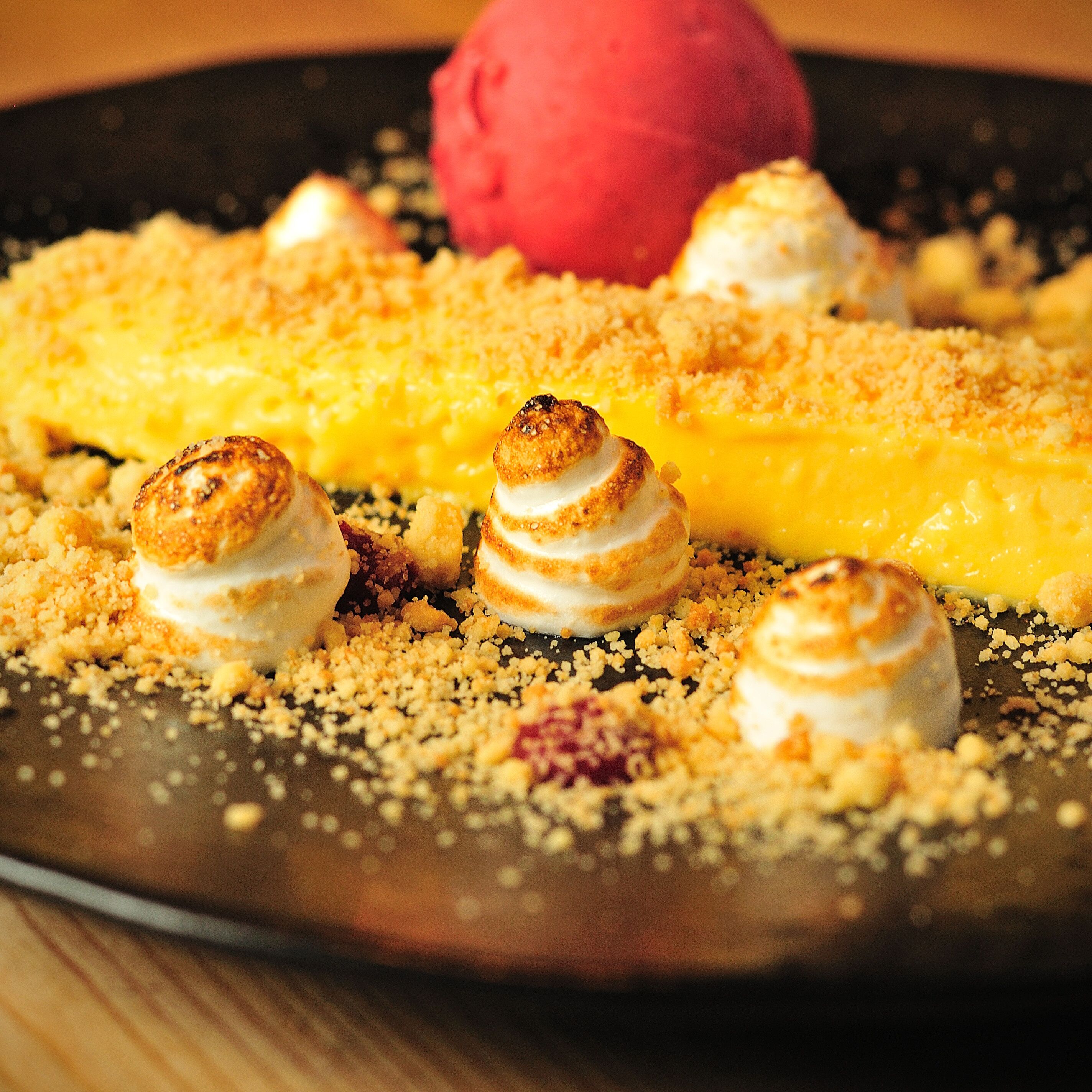 Un piattino con una pallina di gelato e tre marshmallow guarniti con briciole.