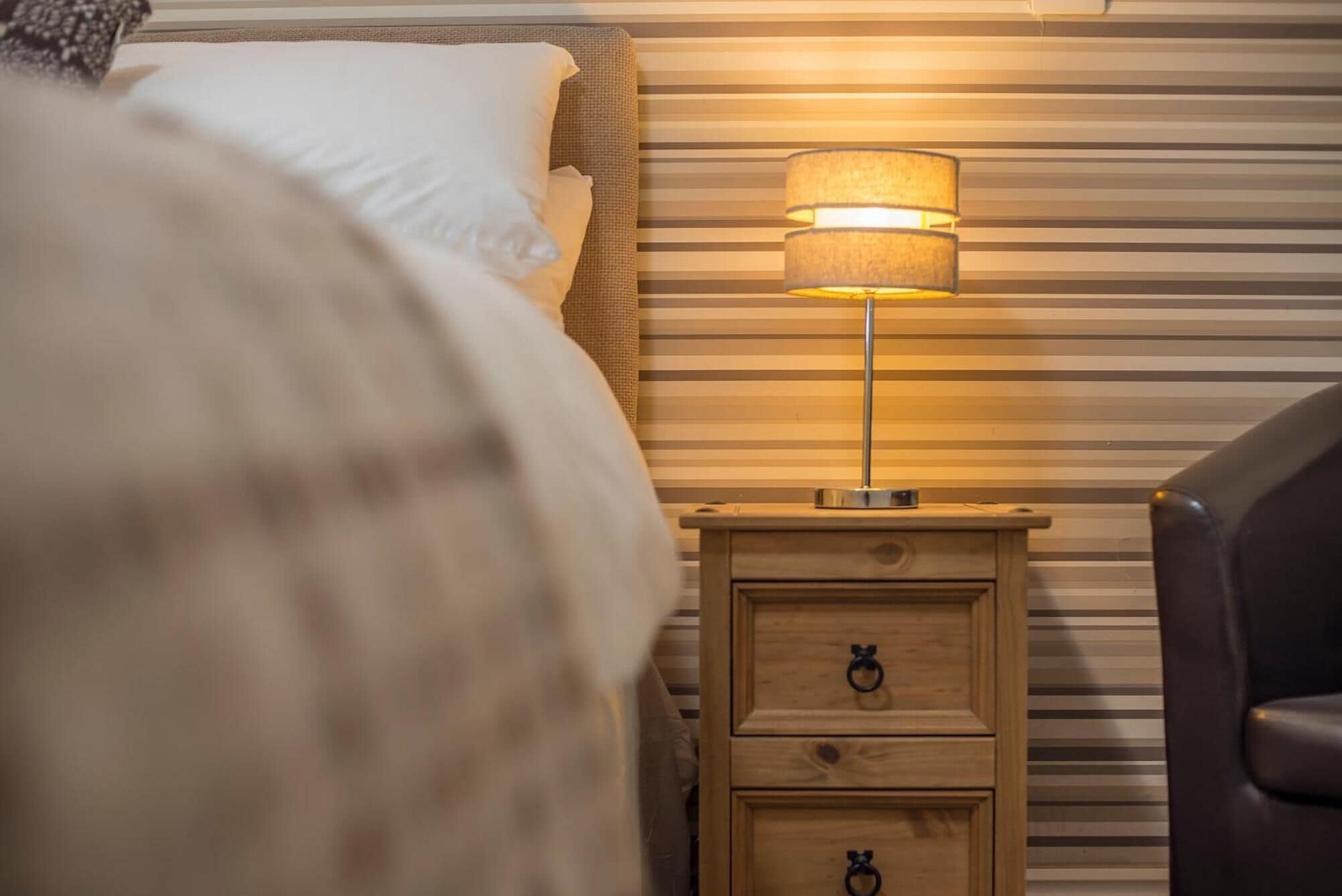A bed with white pillows and a striped wall in the background.