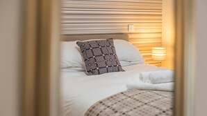 A neatly made bed with white linens, a patterned pillow, and a rolled towel on the side. - The Nag's Head Inn (Boncath)
