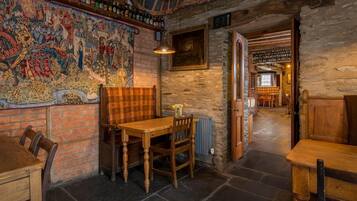 A rustic interior with a stone wall, a large tapestry, and wooden furniture.