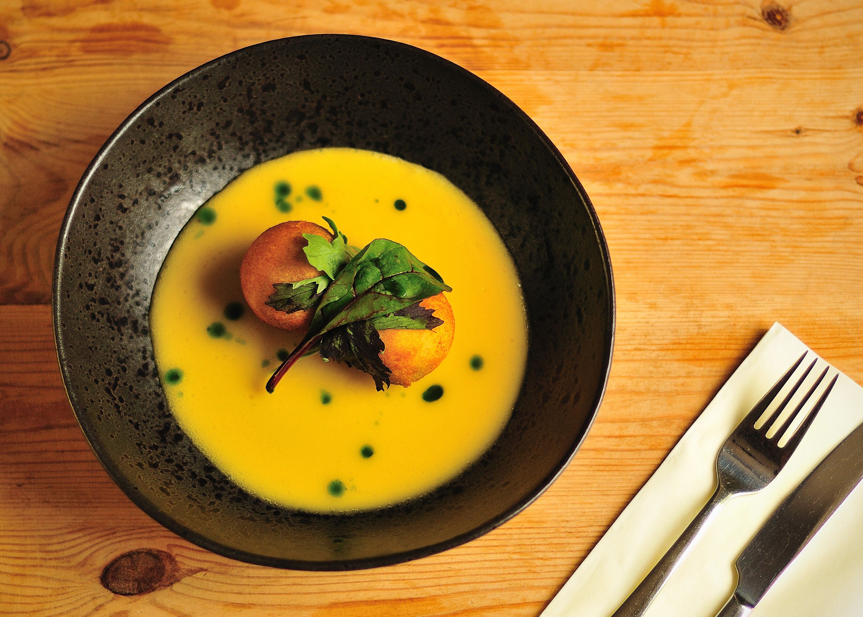 A bowl of soup with a garnish on a wooden table.