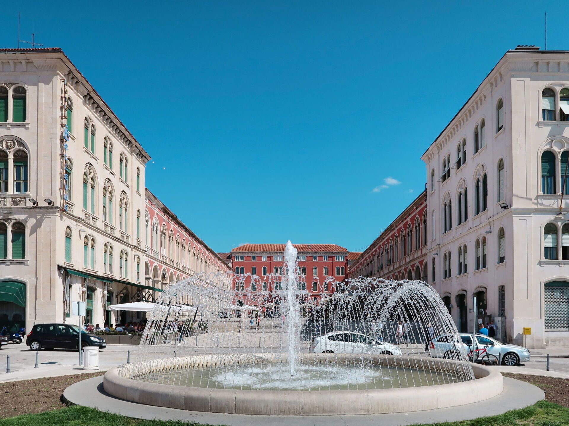 Une fontaine publique avec des jets d’eau au centre, entourée d’une promenade circulaire.