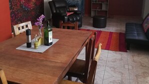 A dining area with a wooden table, chairs, a bookshelf, and a sofa. - vrinda wasi 108 (Lamay)