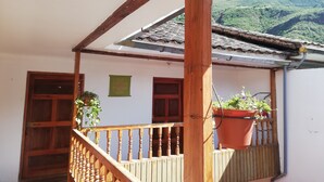 A wooden balcony with a tiled roof, a wooden railing, and a potted plant. - vrinda wasi 108 (Lamay)