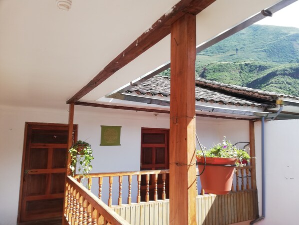 A wooden balcony with a tiled roof, a wooden railing, and a potted plant.