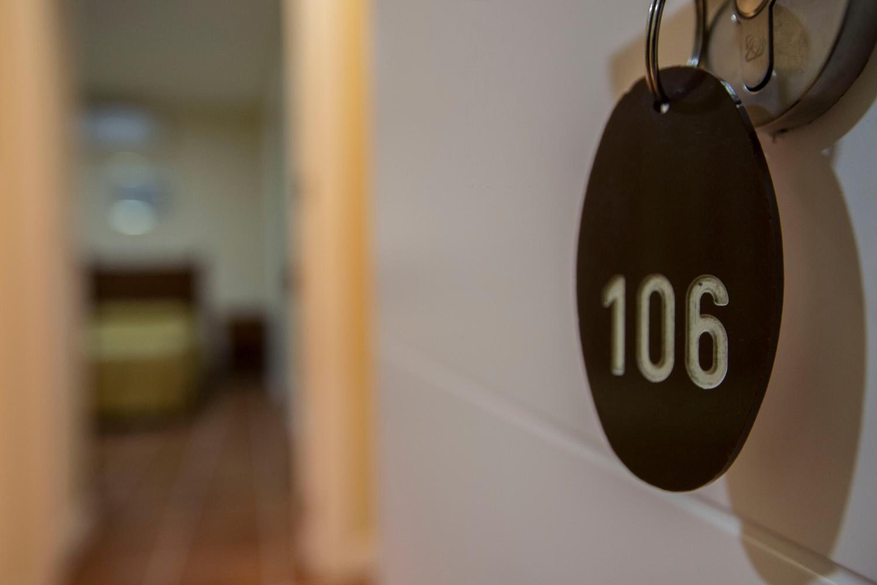Une vue rapprochée d’une plaque noire portant le numéro de chambre 106, fixée à un mur.