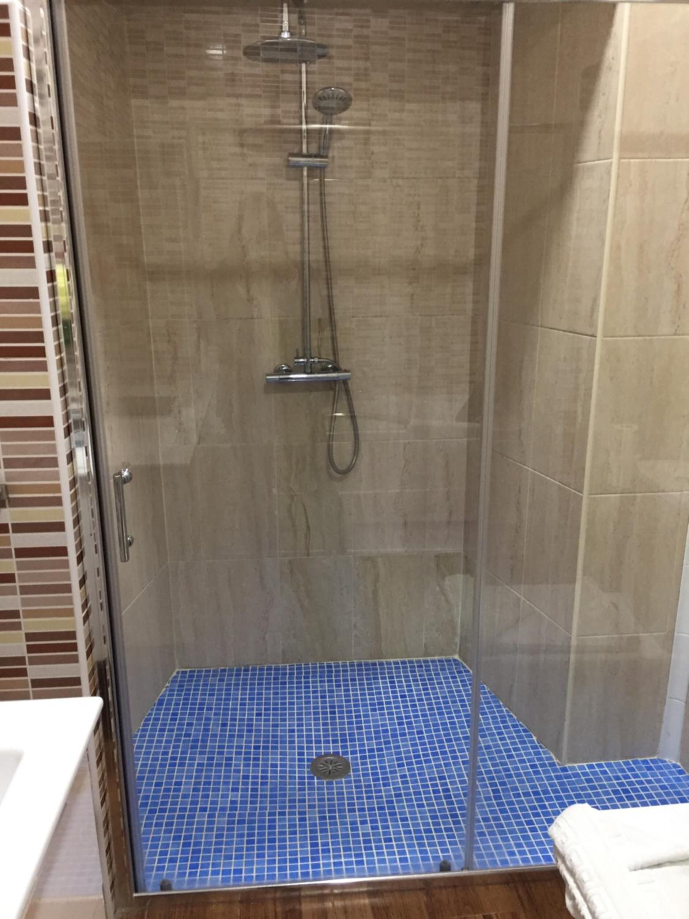 A walk-in shower with a tiled floor and a glass door.