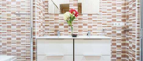 Un baño con salpicadero de azulejos, un lavabo blanco y un espejo encima.