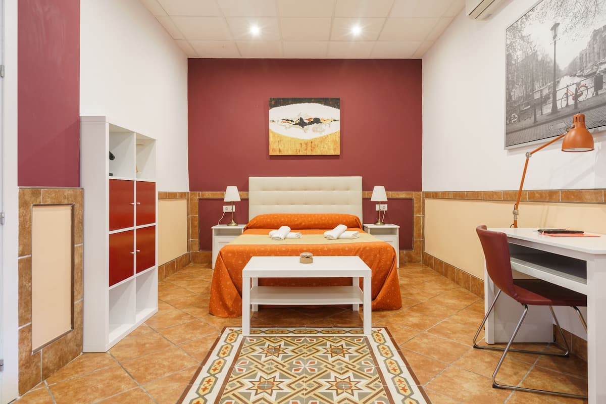 Un dormitorio con cama, mesitas de noche, escritorio y una silla.