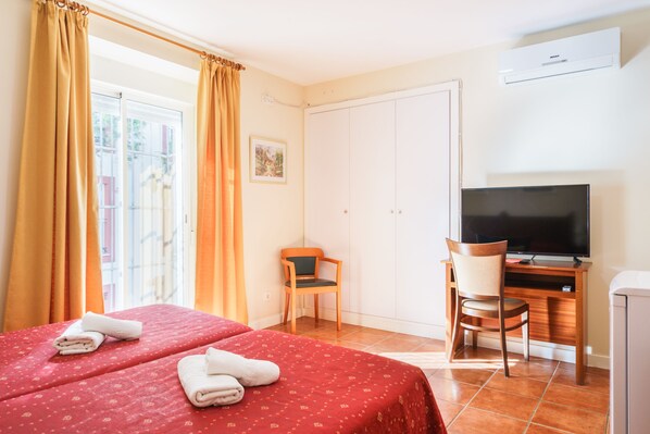 Una habitación de hotel con dos camas, televisión, escritorio y una silla.