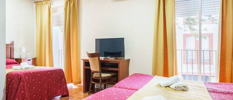 Een hotelkamer met twee bedden, een bureau met een stoel, een televisie en een airconditioner.