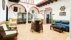 A hotel lobby with a high ceiling, a central bar area, and a blue sofa. - Hotel Carlos V by Viverestays (Jerez de la Frontera)
