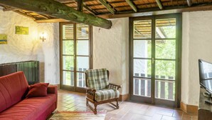 Una habitación acogedora con un sofá rojo, un sillón escocés y una alfombra estampada.