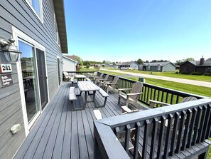 Une terrasse avec des tables et des chaises pour pique-niquer, un ciel dégagé et une rangée de maisons en arrière-plan.