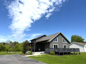 Une maison à deux étages avec un porche, un patio couvert et une pelouse bien entretenue.