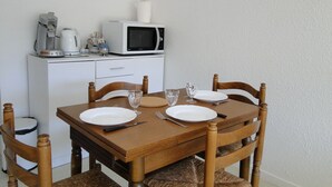 A dining table set with plates, cutlery, and glasses, with a microwave and coffee maker on a cabinet in the background. - Comfortable studio with view of pond and Chateau (Chauffailles)