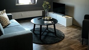 Un soggiorno moderno con un divano, un tavolino, una TV e un termosifone.