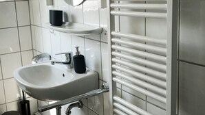 Un bagno con lavandino bianco, specchio e portasciugamani.