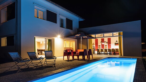 Una casa moderna con piscina, area relax esterna e interni luminosi.