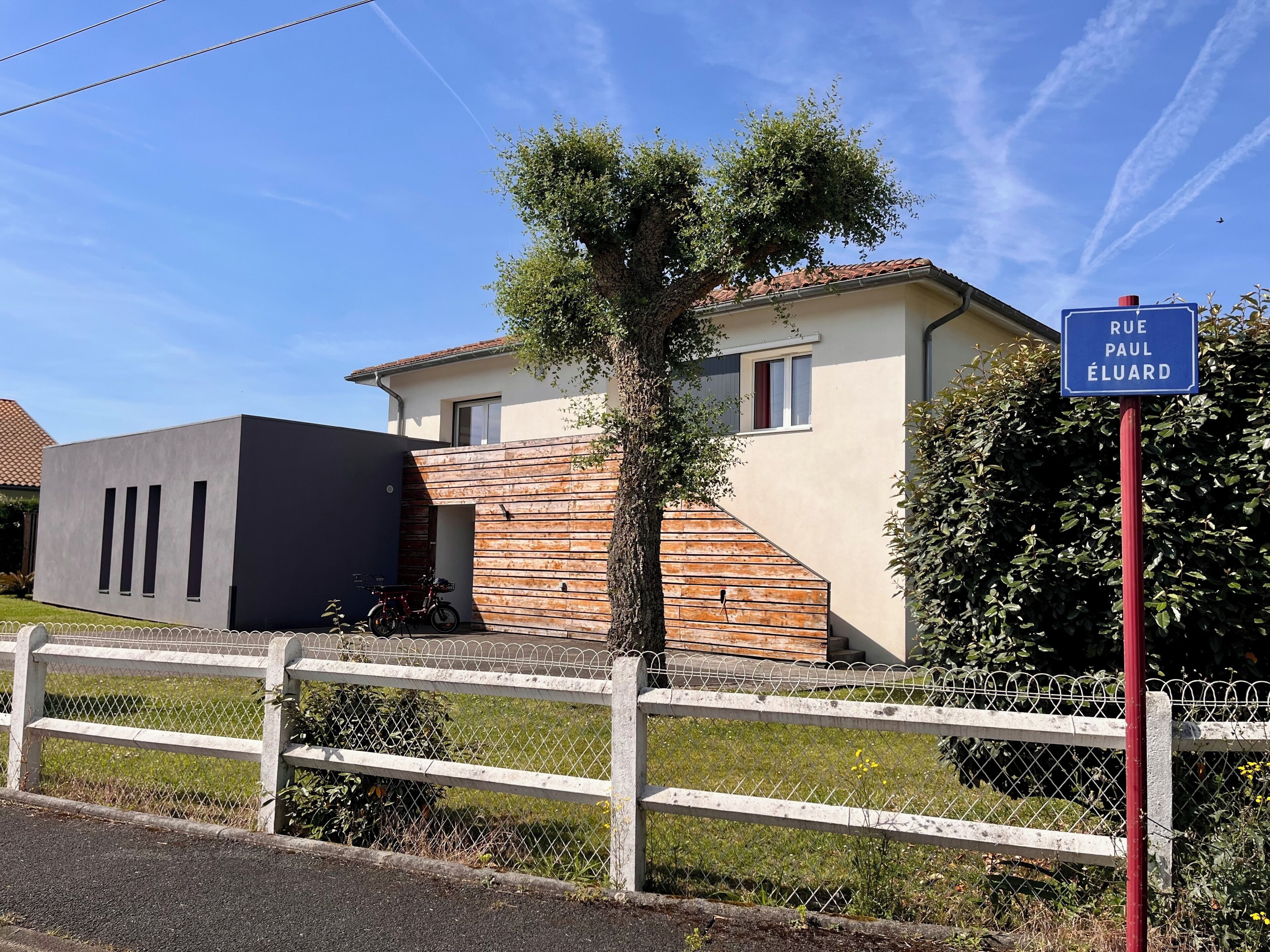 Propiedad residencial con una casa moderna, patio cercado y un letrero que indica el nombre de la calle.