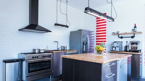 A modern kitchen with stainless steel appliances, a wooden island, and a red and white striped accent wall. - Lavilla2laplage, Tarnos, Landes; shops and beach within walking distance, 7 bedrooms, 5 bathrooms, sleeps 18 (TARNOS)