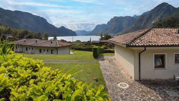 A serene lakeside village with traditional architecture, stone pathways, and lush greenery. - Lovely apartment in villa for 5 guests with WIFI, TV, terrace and pets allowed (Crone)