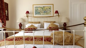 A neatly arranged bedroom with a bed, two bedside tables, a painting on the wall, and a door in the background. - Garfits lodge (Boston)