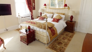 A neatly arranged bedroom with a four-poster bed, a bedside table with a lamp, a small wooden chest, and a large window with curtains. - Garfits lodge (Boston)