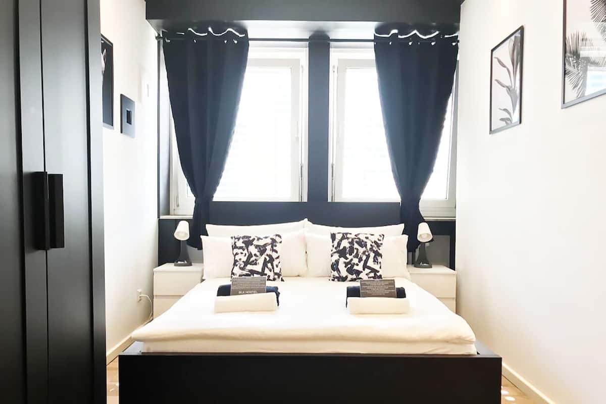 A modern bedroom with a large bed, two bedside tables, and a window with curtains.