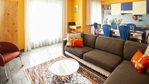 A living room with a sofa, a coffee table, and a dining area with chairs and a table. - Beautiful apartment for 3 people with WIFI, A/C and balcony (Corrido)