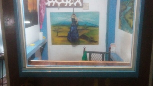 A reception area with a framed painting of a woman in a blue dress, a patterned wall, and a sign that reads "Reception". - Twiga Guest House (Thika)