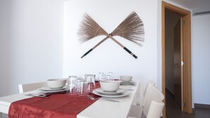 Une table à manger dressée avec de l’assiette blanche, des bols et des verres, ainsi qu’un chemin de table rouge.