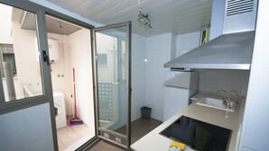 Une cuisine compacte équipée d’une cuisinière intégrée, d’un évier et d’une porte vitrée donnant sur une buanderie.