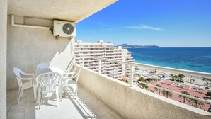 Ein Balkon mit Meerblick, weißen Stühlen und einem Deckenventilator.